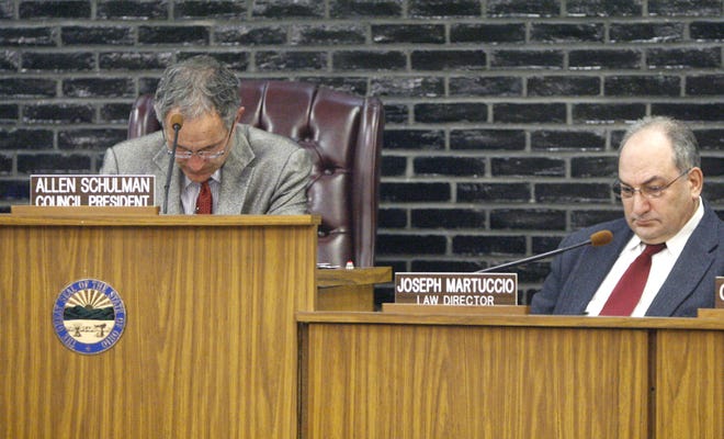 Allen Schulman, council president and Joseph Martuccio, law director, bow their heads in a moment of silence for the victims of the Chardon shootings prior to the Canton City Cuncil meeting Monday.