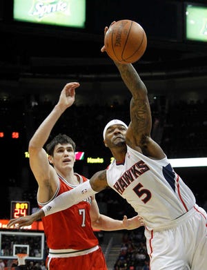 Atlanta forward Josh Smith reaches for a rebound over Milwaukee's Ersan Ilyasova. The Hawks opened the fourth quarter with a 15-3 run to take the lead Friday night.