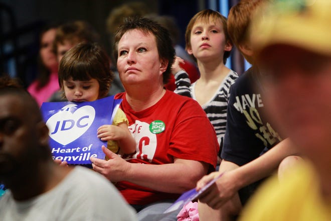 Sara Rochester, a mental health technician at the Jacksonville Developmental Center and her granddaughter, 3-year-old Abigail Sotello, hold signs that read “JDC the Heart of Jacksonville” at Wednesday’s hearing at Illinois
College in Jacksonville. Jason Johnson / The State Journal-Register