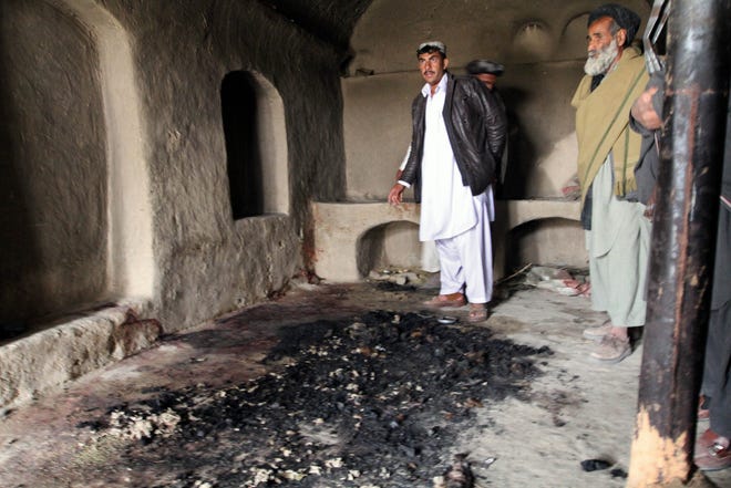 In this Sunday, March 11, 2012 photo, men stand next to blood stains and charred remains inside a home where witnesses say Afghans were killed by a U.S. soldier in Panjwai, Kandahar province south of Kabul, Afghanistan, on Sunday. An Afghan youth recounted on Monday the terrifying scene in his home as a lone U.S. soldier moved stealthily through it during a killing spree, then crouched down and shot his father in the thigh as he stepped out of the bedroom. The soldier, now in U.S. custody, is accused of killing 16 Afghan civilians in their homes in the middle of the night between Saturday and Sunday and then burning some of their corpses. Afghan President Hamid Karzai said nine of those killed were children and three were women. (AP Photo/Allauddin Khan)