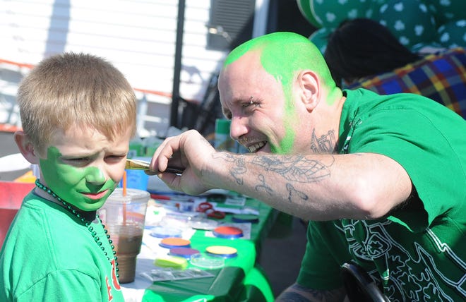 Tim White, owner of Extreme Fantasy in Abington, paints Logan Cote's, 7, of East Bridgewater, face and hair green in preparation for the annual St. Patrick's Day Parade in Abington on Sunday, March 18, 2012.