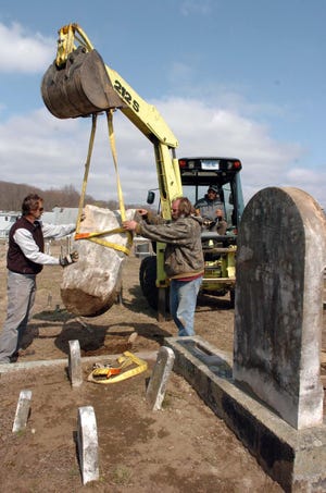 Paul Daniels, left, Rob Spielvogel and Ray Thompson, in backhoe, of Norwich Public Works, lift a gravestone into place. The mild winter has allowed crews to do work they normally do later in the year.