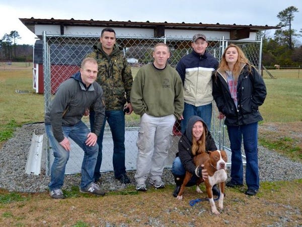 From left, standing: Scott Gornall, Taylor Meave, Dan Coran, Kevin MacDevette and Delane Neuroth. Topsail Humane Society shelter manager Ami McArthur holds onto Collista, one of the shelter’s dogs. The Marines put up the ‘bully-friendly’ shelter on a rainy Sunday. Contributed photo.