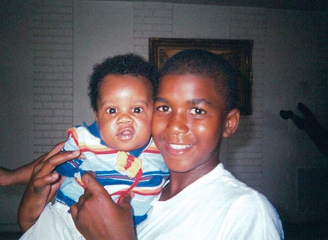 In this undated photo provided by the Martin family, Trayvon Martin holds an unidentified baby. Martin, 17 of Miami Springs, Fla., was killed by a neighborhood watchman following an altercation in Sanford, Fla. as he walked from a convenience store in February, 2012. (AP Photo/Martin Family, File)