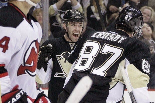 Pittsburgh Penguins' Pascal Dupuis, center, celebrates his second period goal with teammate Sidney Crosby (87) during an NHL hockey game against the New Jersey Devils in Pittsburgh Sunday, March 25, 2012. (AP Photo/Gene J. Puskar)