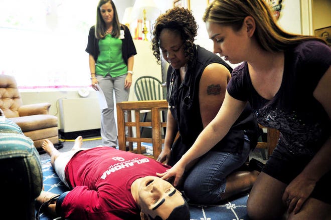 EMT Tikishi Herring (center) and paramedic Alexcia Geary check the vital signs on a training dummy while neuroscience nurse educator Holly Hula looks on during a course about how to care for stroke patients before they get to the hospital.