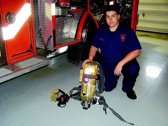 Matt Bowman, 16, junior firefighter president, displays the self-contained breathing apparatus which will be replaced with the most modern style, thanks to a federal grant.