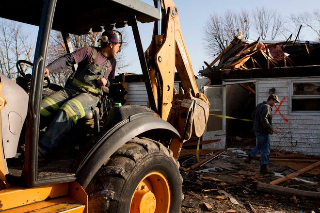 Chase Allen, uses a backhoe and a tow strap to help pull out a love seat from the collapsed apartment of Cody Horton, right, that was struck by a tornado in Harrisburg, Ill., Wednesday, Feb. 29, 2012. Cody Horton was in the apartment with his girlfriend, Courtney Wilson, and survived by diving into the bathroom tub.