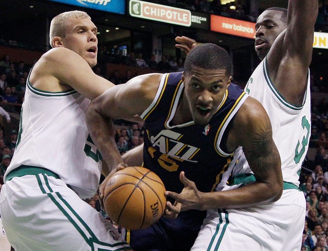 Jazz forward Derrick Favors (15) drives between Celtics center Greg Stiemsma, left, and forward Brandon Bass, right, in the first half of Wednesday's game in Boston.
