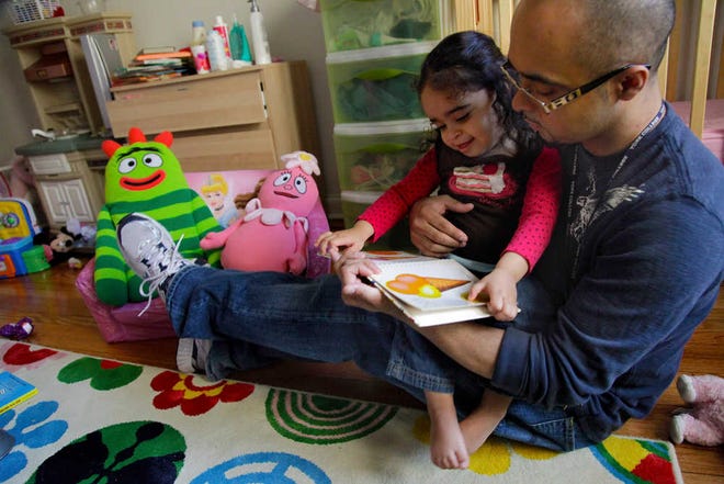 Christopher Astacio reads with his daughter Cristina, 2, recently diagnosed with a mild form of autism, in her bedroom on Wednesday, March 28, 2012 in New York.  Autism cases are on the rise again, largely due to wider screening and better diagnosis, federal health officials said Thursday, March 2012. (AP Photo/Bebeto Matthews)