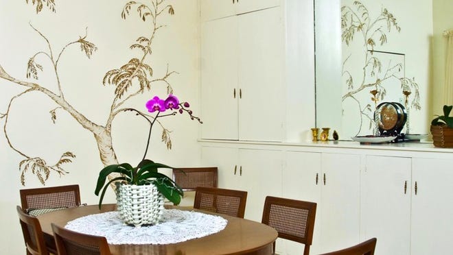With a fanciful mural of a tree on one wall, the dining room has built-in storage cabinets on one side.