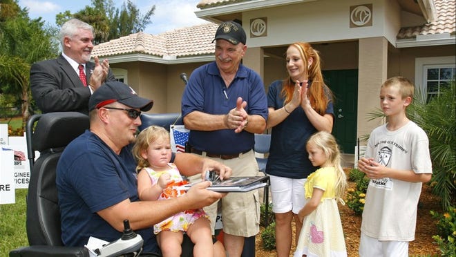 Sgt. 1st Class Steven Holloway, holding daughter Isabelle, receives the keys to his new home Saturday in Wellington. Palm Beachers raised $25,000 for the project. Watching, from left, are Larry Gill, veteran’s liaison for Homes For Our Troops; project general contractor Wally Sanger; wife Laurie; daughter Stephanie; and son Steve.
