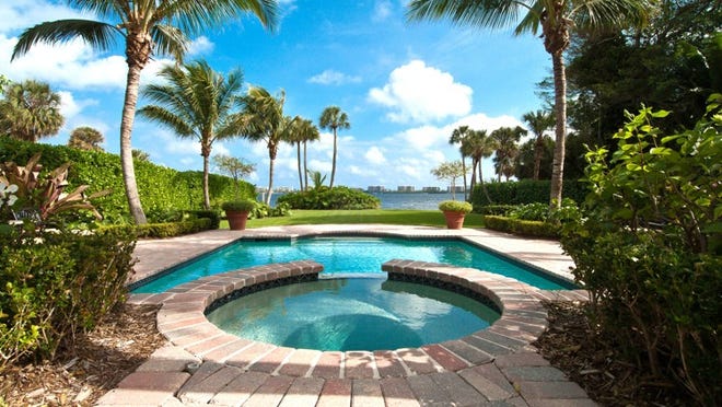 The circular whirlpool spa has a waterfall that drops into the swimming pool behind a home on the Intracoastal Waterway, across from Palm Beach.