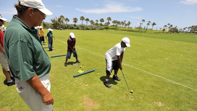 Lew Crampton instructs Keon Johnson, 12, who was practicing his chipping stroke Monday at the Par 3 Golf Course as part of the Hook-A-Kid on Golf program.