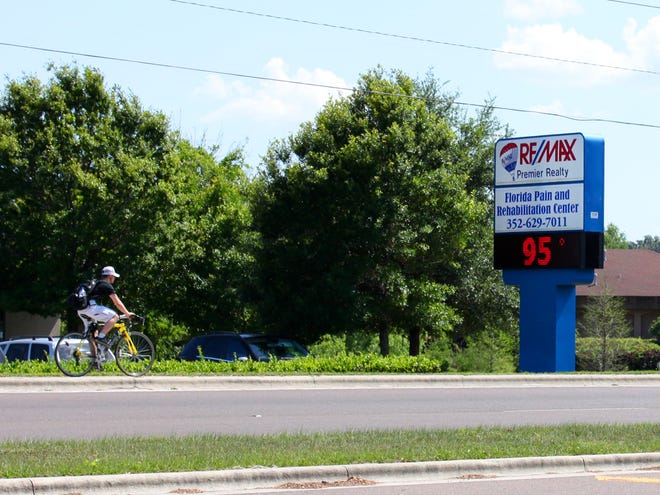 A bicyclist passes a sign on Southwest 19th Avenue Road indicating a hot day in Ocala on Tuesday afternoon. According to the National Weather Service the temperature was actually 90 degrees when this photo was taken.