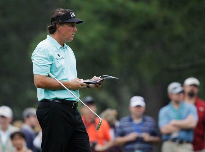 Phil Mickelson checks his notebook on the first green during a practice round for the Masters golf tournament Tuesday, April 3, 2012, in Augusta, Ga. (AP Photo/Charlie Riedel)