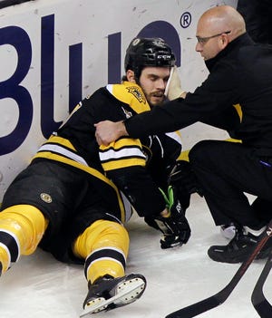 Boston Bruins defenseman Adam McQuaid (54) is attended to by a trainer after he was checked hard in the boards by Washington Capitals left wing Jason Chimera during the first period of an NHL hockey game in Boston, Thursday, March 29, 2012. McQuaid left the game.