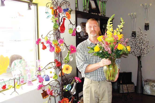 Owner Todd Cannon poses for a photo with a floral arrangement at Bloom Floral Design and Gifts, Ltd.