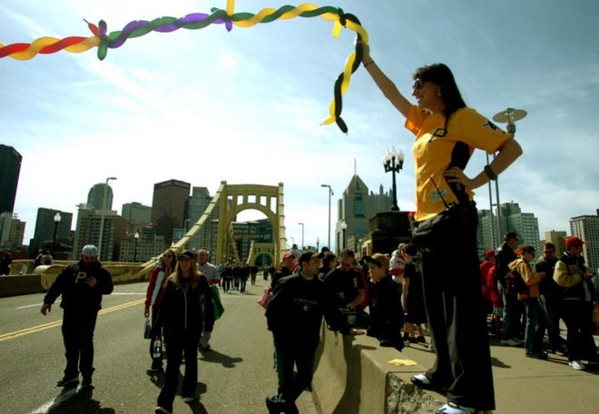 Debbie Bender of Dormont, a member of the Pirates Canonball Crew, greets fans as they walk across the Clemente Bridge.