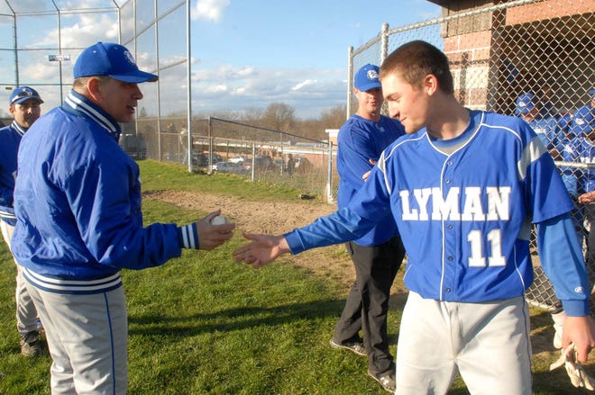 Lyman Memorial coach Marty Gomez, left, gets the game ball from Ben Strenkowski on Wednesday after the Bulldogs beat Windham Tech, 9-1, in Lebanon. The victory was Gomez’s 400th as coach.