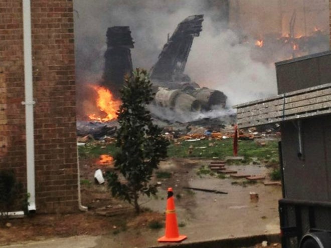 The burning fuselage of an F/A-18 Hornet lies smoldering after crashing into a residential building in Virginia Beach, Va., on Friday, April 6, 2012. (AP Photo / Kandice Angel)