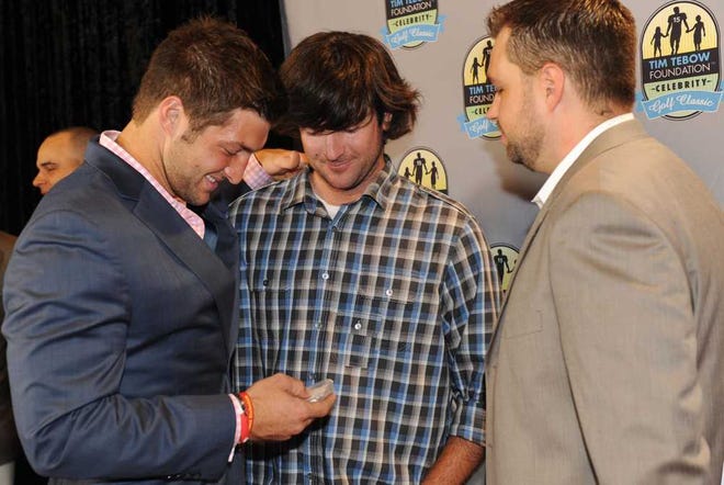 Bob.Mack@jacksonville.com Masters champion Bubba Watson (center) presents Tim Tebow (left) with Watson's Masters badge at an event for the Tim Tebow Foundation Celebrity Golf Classic on Friday night. The badge is No. 15, which is Tebow's number.