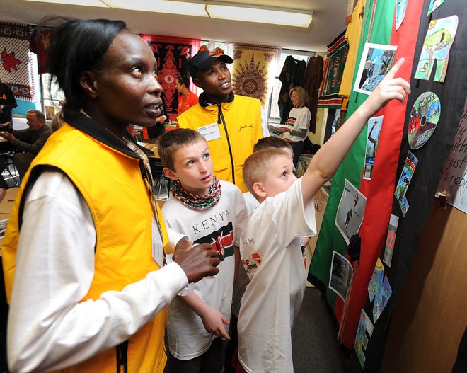 DAILY NEWS PHOTO BY ALLAN JUNG
12 april 2012 thur
 Kenyans visit with 3rd graders at the Elmwood School in Hopkinton
Last year's winners Caroline Kilel and Geoffrey Mutai listen as David Piacientini and Connor Murphy tell them about the banner bearing their names that they will run through during the welcome rally.