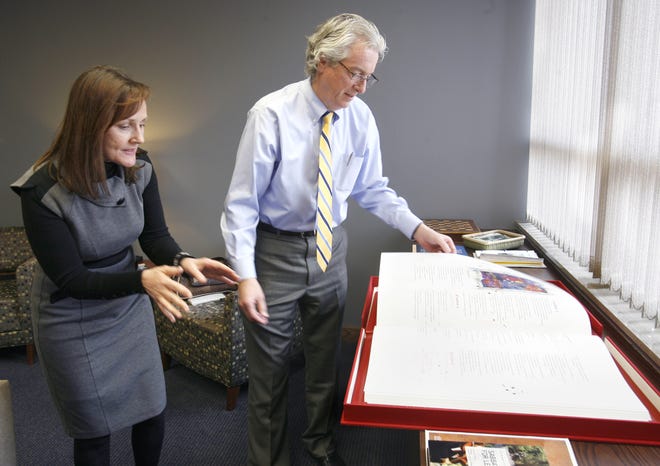 Malone president David King and PR Director Suzie Thomas look at a Bible in King's office. Only several hundred of them were produced.