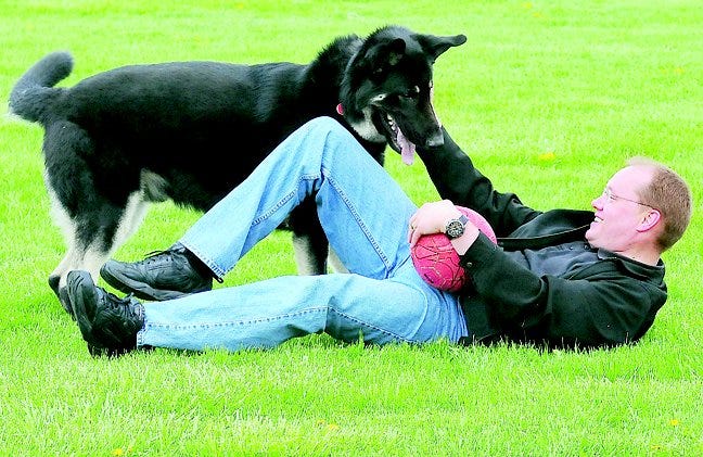 Matthew Varnum of Adrian plays with his service dog, Shadow. Varnum suffered a traumatic brain injury after a 2006 car crash.