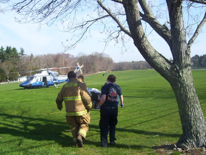 Firefighters take a 13-year-old Holliston cyclist to a medical helicopter after an accident on Monday.