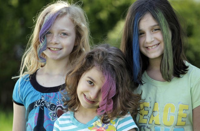 In this photo taken, Monday, April 2, 2012, Maddie Parizek, Sadie Moussa, and Gabriella Lujan, left to right, show off their hairstyles created with soft pastel chalk applied by neighborhood mom Orly Telisman in Chicago. Everyone from hipsters to children to Hollywood celebrities is embracing the runway fad for brightly colored hair, using soft pastel chalk. (AP Photo/M. Spencer Green)