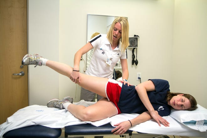 Physical therapist Kailin Collins shows Lauren Wooley exercises she can do for her hip pain at a free post-Marathon athlete injury clinic at Newton-Wellesley Hospital. Wooley says this is her fourth time running the Boston Marathon and the heat made it much more difficult this year.