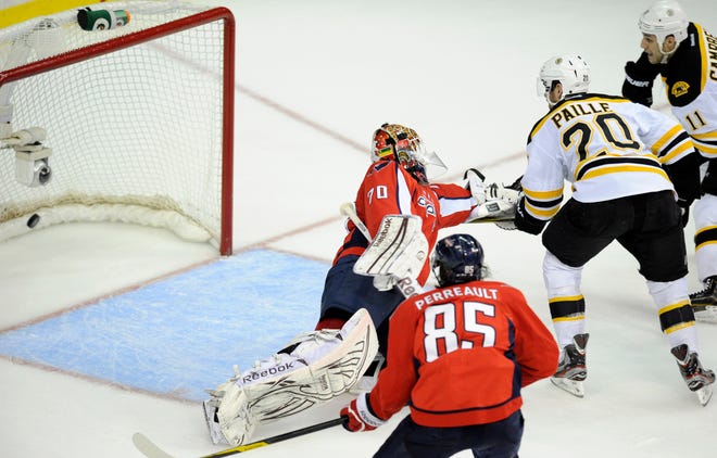 Boston Bruins left wing Daniel Paille (20) looks at the puck in the goal after he scored against Washington Capitals goalie Braden Holtby (70) during the second period of Game 3 of an NHL hockey Stanley Cup first-round playoff series, Monday, April 16, 2012, in Washington. In front is Capitals' Mathieu Perreault (85).