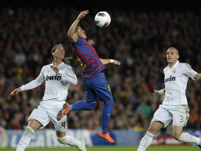 Barcelona's Alexis Sanchez from Chile, center, duels for the ball with Real Madrid's Sergio Ramos, left, and Pepe from Portugal during a Spanish La Liga soccer match at the Camp Nou stadium, in Barcelona, Saturday, April 21, 2012.