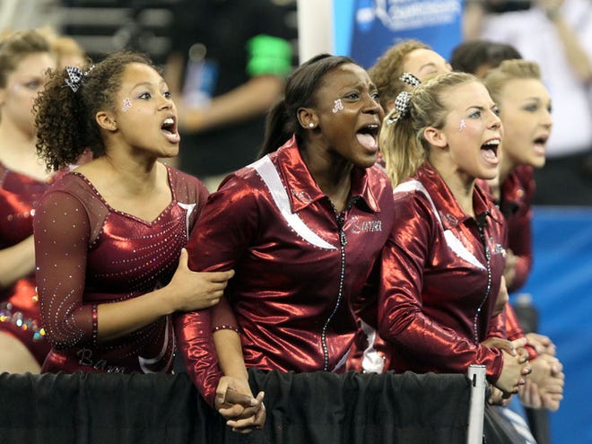 University of Alabama gymnasts (from left) Diandra Milliner, Hunter Dennis and Lora Leigh Frost cheer on teammate Kayla Williams during her beam exercise Friday at the NCAA gymnastics semifinal session at the Arena at the Gwinnett Center in Duluth, Ga.