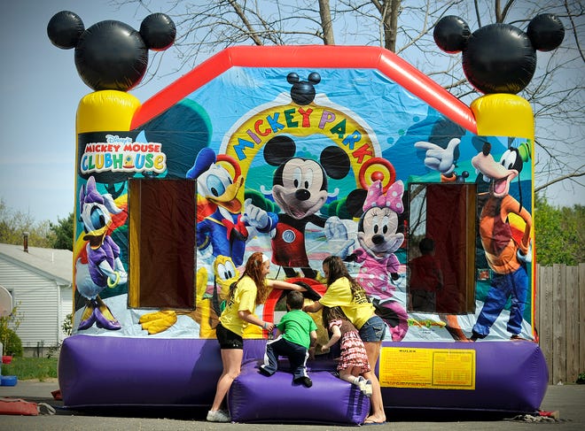 Kylie Coffey, left, and Kirsten Coffey of Busy Bee Jumpers attend to children as they play on a Mickey Mouse inflatable.