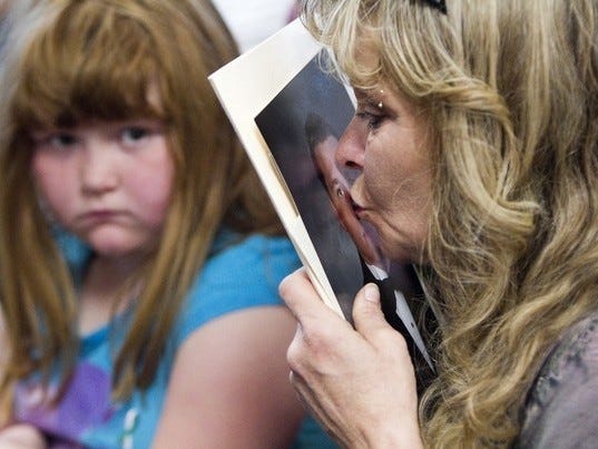 Lindie Reiss kisses a picture of her son Jacob Smith, who was murdered, while attending the Victims' Remembrance Ceremony Thursday in the jury assembly room in the Marion County Judicial Center in Ocala. About 300 people attended the annual event that is held in honor of Victim Rights Week. About 150 victims from Marion County were honored. (Doug Engle/Star-Banner)