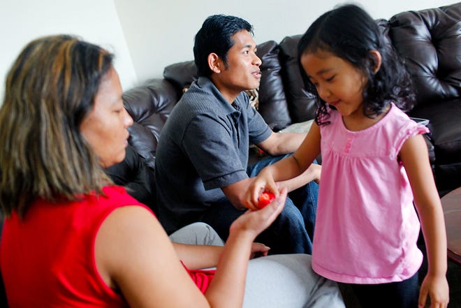 Dim Sian Kim, 4, hands her mother, Vung Lun Cing, a strawberry while her father, Thang Khen Pau, speaks at their home in Columbia. Pau and Cing, a Burmese couple, are refugees who worked for Jen Wheeler’s Safi-Sana cleaning company when they first arrived in Central Missouri.
