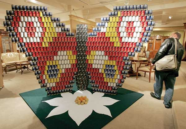 AP Photo/Kathy Willens In a 2005 file photo, Gavin Schmidt, right, of New York, takes a walk around a butterfly made entirely of cans at “Canstruction” in New York. A similar Canstruction challenge will be part of Foodstock 2012.