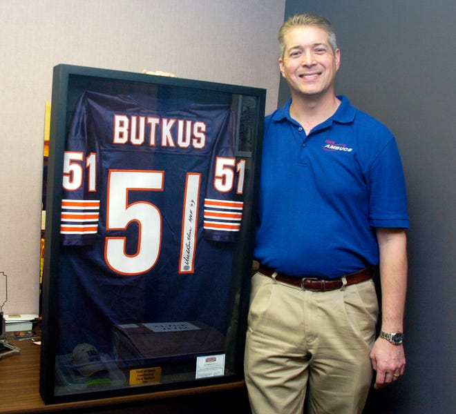 Pekin AMBUCS president Bill Calvert shows off a framed Bears jersey autographed by Chicago Bears Hall of Fame linebacker Dick Butkus, which is his favorite of about 100 celebrity items that will be part of the AMBUCS 41st annual charity auction Friday at the Pekin Park District Arena. The auction also features thousands of new and used items, as well as gift certificates.