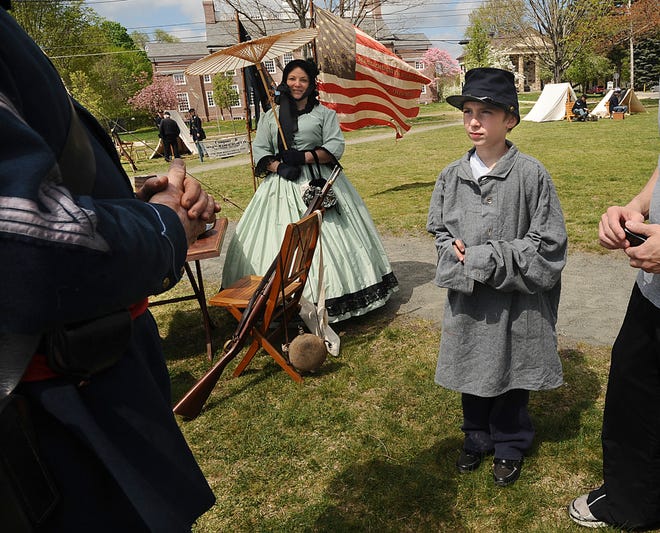Matthew Giovine, 10, of Framingham, tries on a Union uniform while talkingto reenactor Gus Gallagher of Holden, left, a Sgt. Major in the Union 25th Massachusetts Volunteer Infantry, during a training session in advance of a Civil War Encampment on May 4-6 on Framingham Centre Common. Behind them is Gus Gallagher's wife Susan.