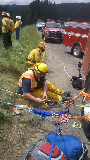 Mount Shasta City Fire Department volunteers Cory Burns and Tyler Witherell prepare rigging to rescue four people from a car which plummeted down a 100 foot embankment on Interstate 5 near Castella last Tuesday, April 24.