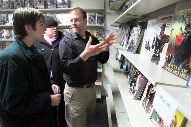 Brad Price, owner of Alternate Realities, discusses comic books with customers Charles Ely, left, and Lauren Reid in the business in the lower level of Weaver Main Street Center.