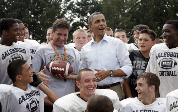 President Barack Obama hands off a football to Galesburg High School football coach Tim Dougherty during a surprise visit to Silver Streaks practice Aug. 17. He also met members of the GHS volleyball team.
