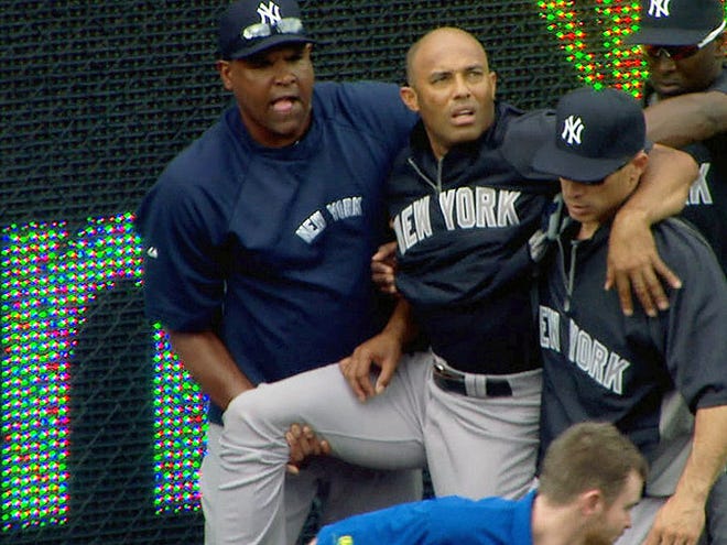 In this image taken from video, New York Yankees manager Joe Girardi, right, helps Mariano Rivera, top center, after Rivera twisted his right knee shagging fly balls during batting practice before a baseball game with the Kansas City Royals, Thursday, May 3, 2012, in Kansas City, Mo. The Yankees closer was carted off the field and sent for further tests. (AP Photo/YES Network) MANDATORY CREDIT
