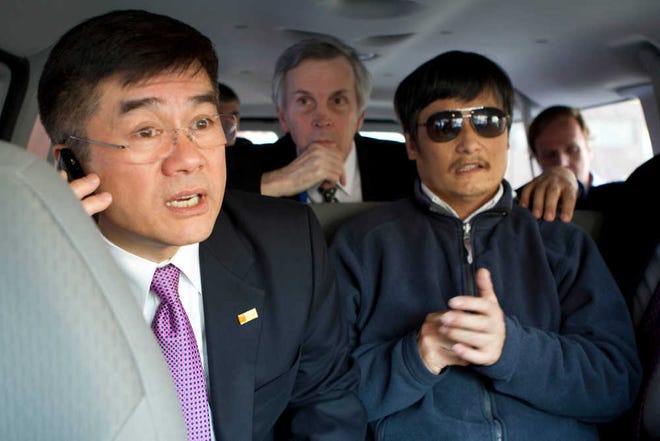 In this photo released by the U.S. Embassy Beijing Press Office, U.S. Ambassador to China Gary Locke, left, makes a phone call Wednesday as he accompanies blind lawyer Chen Guangcheng, right, in a car en route from the embassy to a hospital in Beijing.