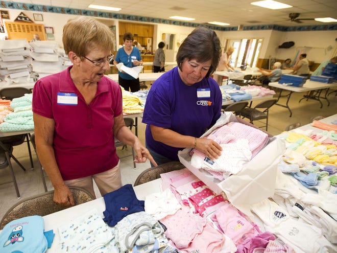 Seniors 4 Newborns member Donna Schwartz, left, shows Kohl's associate Karen Decker how to pack sets of baby items to be given to new babies at the Oak Bend clubhouse on March 28, 2012, in Ocala.