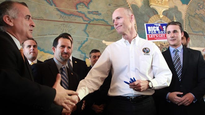 Gov. Rick Scott shakes hands with Dade County Commissioner Esteban Bovo after signing Bill 959, which would prohibit Florida companies from doing business with Cuba, on May 1, 2012 at Miami's Freedom Tower.