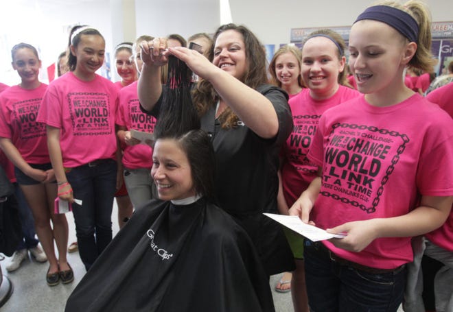 Amy Staubs of Akron (center) listens to Brittany Hunt, 13 (right) explain why the group of Revere Middle Schoolers, who were taking part in the tradition of Rachel's Challenge, were paying for her hair cut as stylist Nancy Morris continues to cut her hair at Great Clips in the Fairlawn Town Centre on Saturday in Fairlawn, Ohio.(Mike Cardew/Akron Beacon Journal)