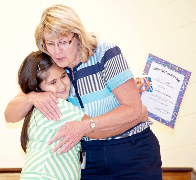 Dolores Garrigan, a third-grade teacher at Charles England Elementary School, congratulates her student, Yasmely Montes-Chavez, after the young girl is presented with a recognition award for outstanding citizenship Monday at the school.
